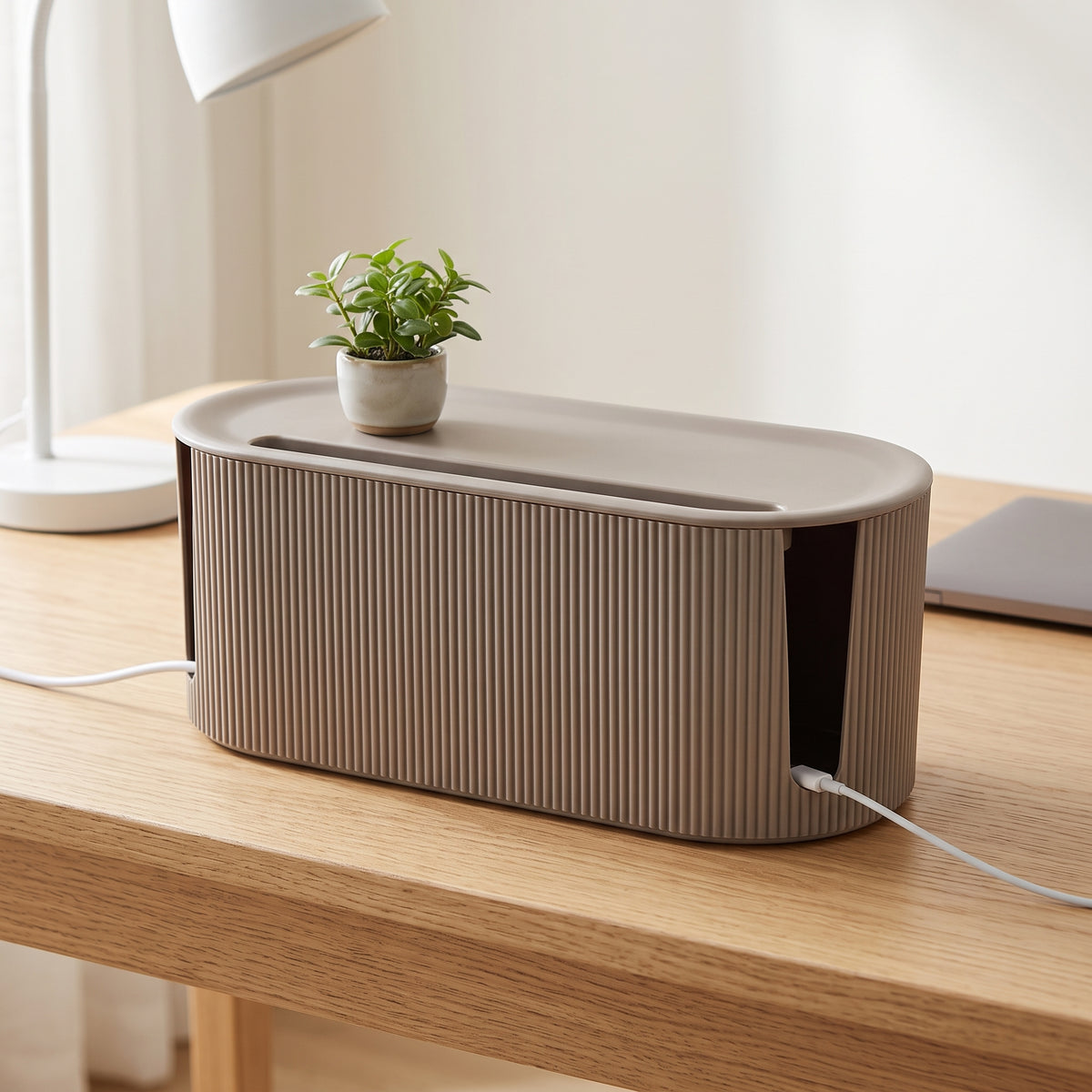 Sfeerbeeld: CableBox op een houten bureau, kabels komen via de openingen aan de zijkanten naar buiten